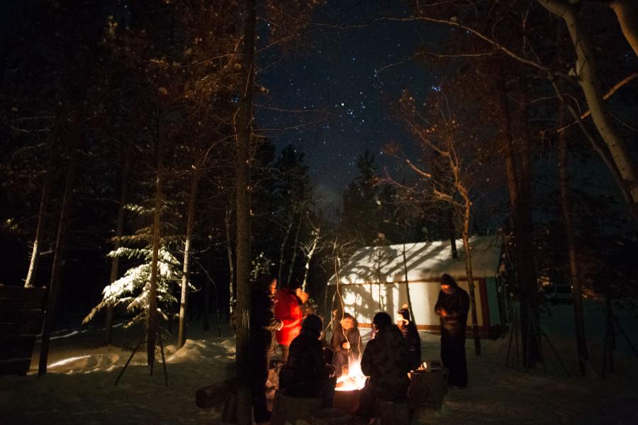 Grupo alrededor de una fogata bajo un cielo estrellado en invierno
